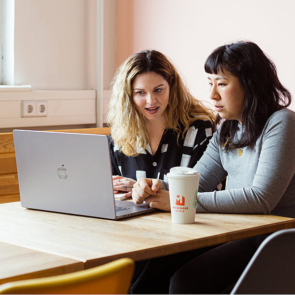 Dwie kobiety korzystające z laptopa do łatwiejszej rezerwacji i przeglądania w hotelach MEININGER