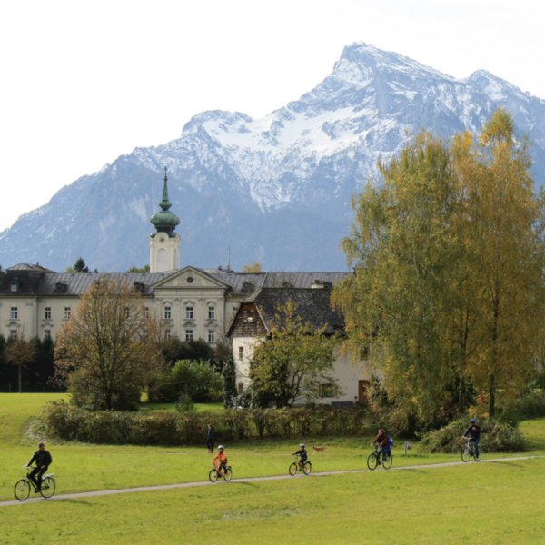 Famiglia in bicicletta vicino a una chiesa paesaggistica e montagne a Salisburgo