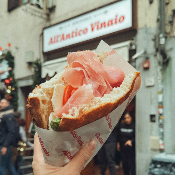 Mano che tiene un panino al prosciutto a Roma, Italia
