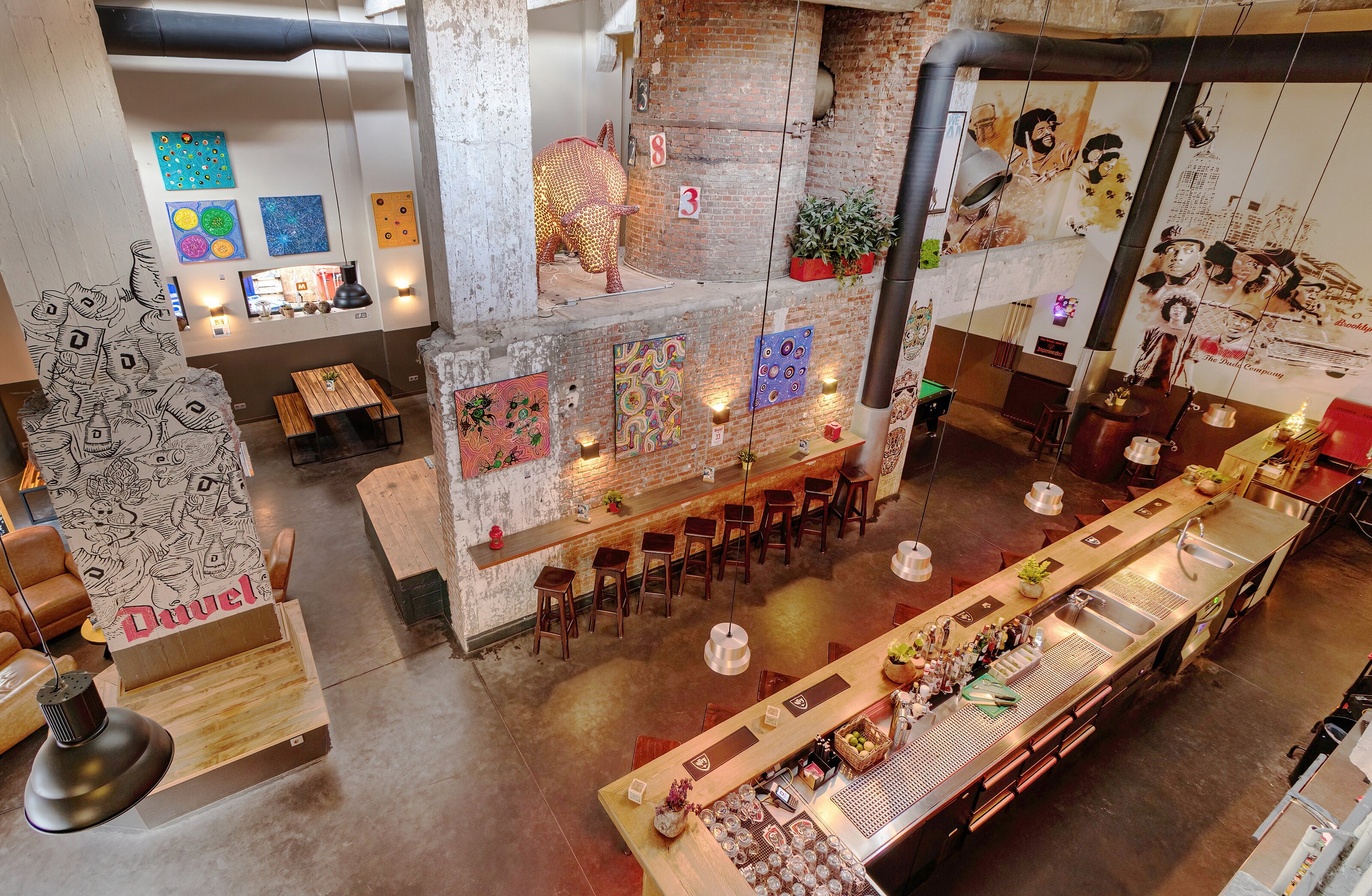 Industrial-style common area at MEININGER Hotel Brussels City Center with vibrant bar and cozy seating.